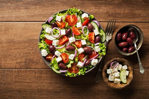 Salad with feta cheese and fresh vegetables on wooden background. Greek salad.