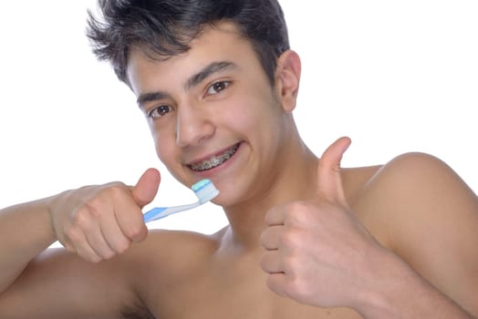 Cute teenager with white background, wearing braces on his teeth. Use toothbrush and toothbrush for cleaning.