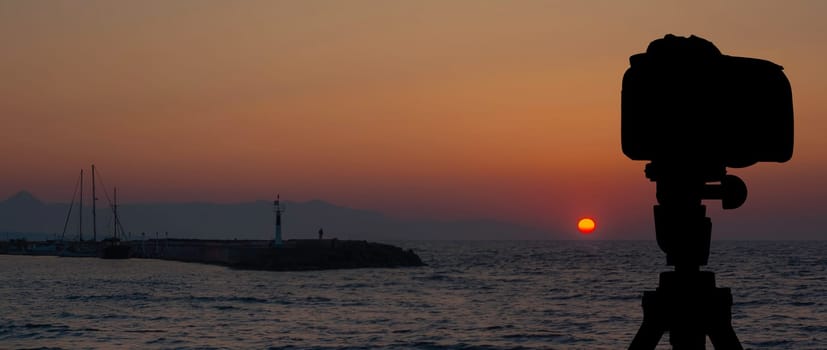 Camera on tripod with sea and sunset in background / Gouves, Crete, Greece