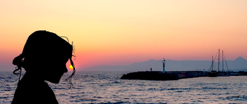 Silhouette of a young girl with sunset over the sea in Gouves, Crete, Greece