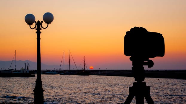 Camera on tripod with sea and sunset in background / Gouves, Crete, Greece