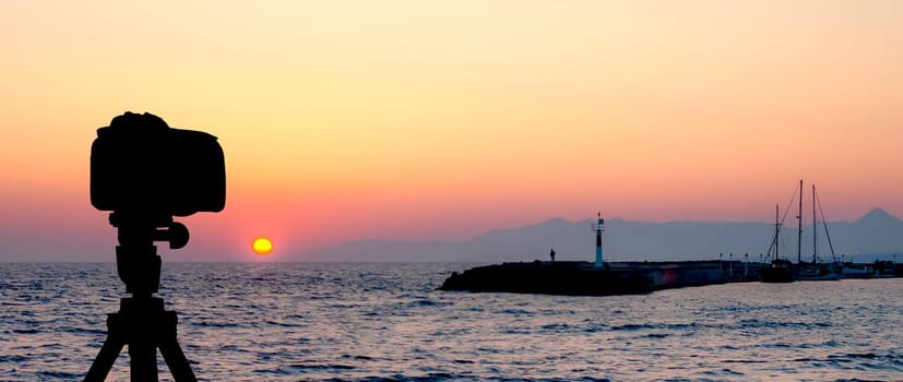 Camera on tripod with sea and sunset in background / Gouves, Crete, Greece