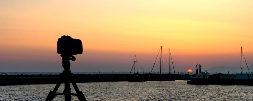 Camera on tripod with sea and sunset in background / Gouves, Crete, Greece