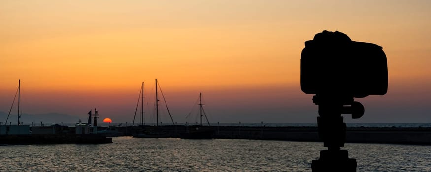 Camera on tripod with sea and sunset in background / Gouves, Crete, Greece