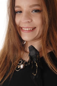 A beautiful young woman in a close up image with long brunette hair.having a fake black bird on her dress, isolated for white background.