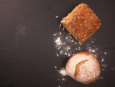 Tasty organic rolls on a dark slate cutting board, natural healthy eating
