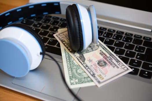 computer keyboard with headphones and dollar bank notes