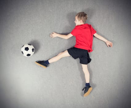 boy in red shirt from above playing soccer ball