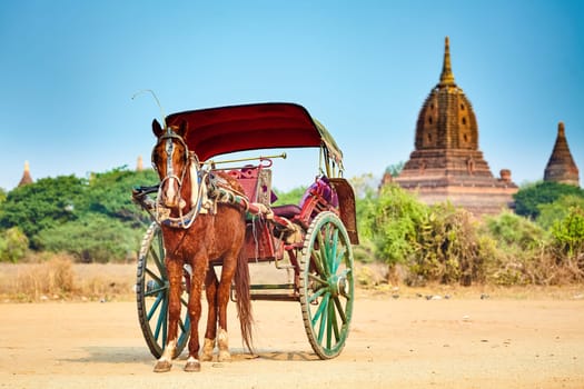 Horses cart waiting for tourist, ancient temple on background. Bagan,Myanmar