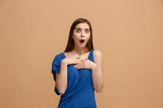 Wow. Beautiful female half-length portrait isolated on pastel studio backgroud. Young surprised woman holding hands by head, looking at camera. Human emotions, facial expression concept. Trendy colors
