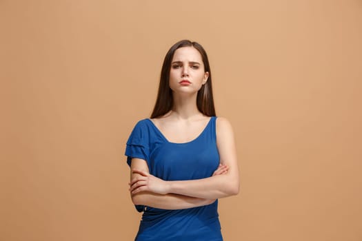 Serious woman standing, looking at camera isolated on trendy pastel studio background. Beautiful, young face. Female half-length portrait. Human emotions, facial expression concept. Front