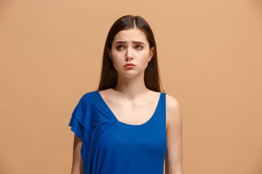 The awkward woman is standing and looking at camera isolated on trendy pastel studio background. Beautiful, young face. Female half-length portrait. Human emotions, facial expression concept. Front