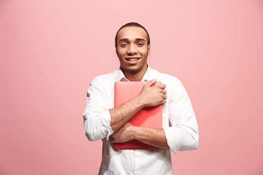 Afro businessman hugging laptop. Love to computer concept. Attractive male half-length front portrait, trendy pink studio backgroud. Young emotional bearded man. Human emotions, facial expression concept.