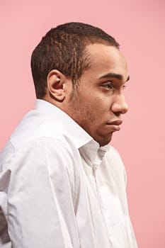 Why is that. Beautiful male half-length portrait isolated on trendy pink studio backgroud. Young emotional surprised, frustrated and bewildered afro man. Human emotions, facial expression concept. Profile