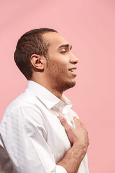 Happy business man standing, smiling isolated on trendy pink studio background. Beautiful male half-length portrait. Young satisfy afro man. Human emotions, facial expression concept. . Profile view.