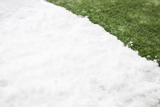 Meeting white snow and green grass close up - between winter and spring concept background. Conceptual image about spring. Selective focus. Background with copy space