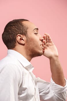 Do not miss. Young casual man shouting. Shout. Crying emotional man screaming on pink studio background. male half-length portrait. Human emotions, facial expression concept. Trendy colors. Profile