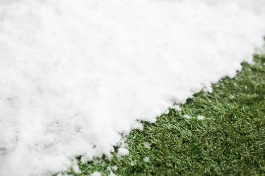 Meeting white snow and green grass close up - between winter and spring concept background. Conceptual image about spring. Selective focus. Background with copy space