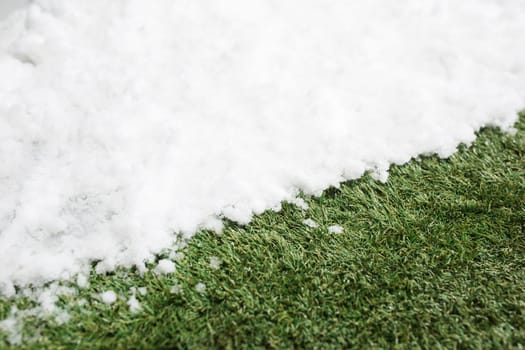 Meeting white snow and green grass close up - between winter and spring concept background. Conceptual image about spring. Selective focus. Background with copy space