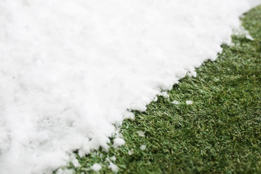 Meeting white snow and green grass close up - between winter and spring concept background. Conceptual image about spring. Selective focus. Background with copy space