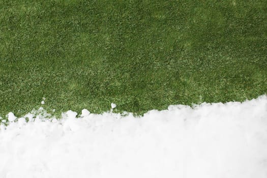 Meeting white snow and green grass close up - between winter and spring concept background. Conceptual image about spring. Selective focus. Background with copy space