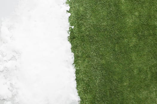 Meeting white snow and green grass close up - between winter and spring concept background. Conceptual image about spring. Selective focus. Background with copy space. Top view