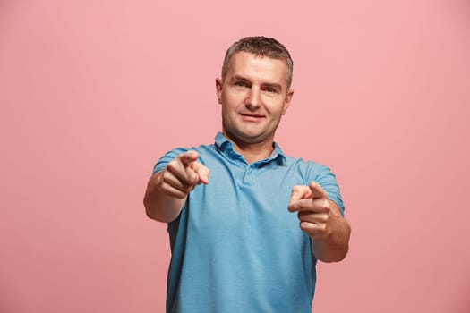 I choose you and order. The smiling business man point you, want you, half length closeup portrait on pink studio background. The human emotions, facial expression concept. Front view. Trendy colors