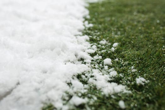 Meeting white snow and green grass close up - between winter and spring concept background. Conceptual image about spring. Selective focus. Background with copy space