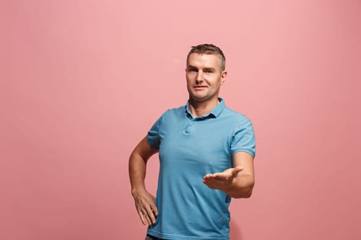Wow. Attractive male half-length front portrait on pink studio backgroud. Young emotional surprised man pointing to camera. Human emotions, facial expression concept. Trendy colors