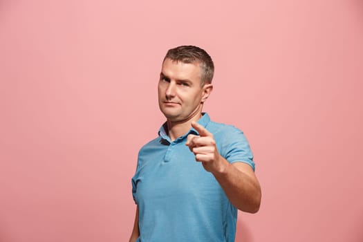 I choose you and order. The serious business man point you, want you, half length closeup portrait on pink studio background. The human emotions, facial expression concept. Front view. Trendy colors