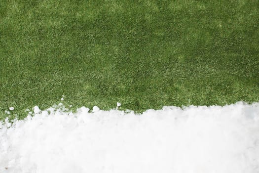 Meeting white snow and green grass close up - between winter and spring concept background. Conceptual image about spring. Selective focus. Background with copy space