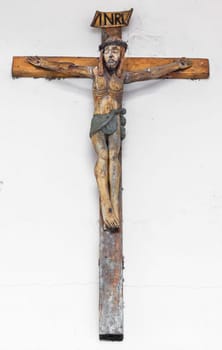 Small wooden crucifix on white background with free space for text.