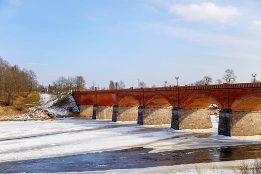 The first spring thawed patches on the river,against the backdrop of a stone bridge