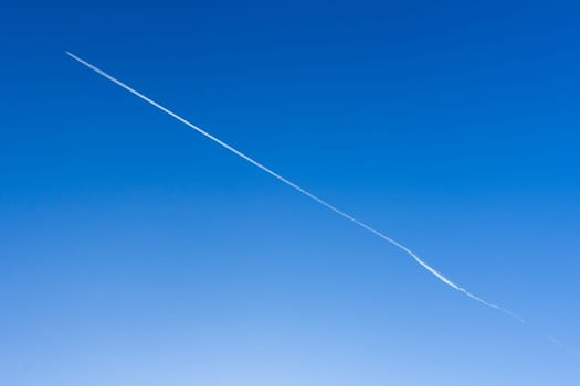 Airplane in the blue sky leaves white stripes behind him. The direction is diagonal. It can be used as a background. Space for text.