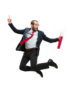 Funny cheerful businessman jumping in air over white studio background. Jump of happy bearded young man in glasses, suit. Business, career, success, win concept. Victory, delight concept. Human facial emotions