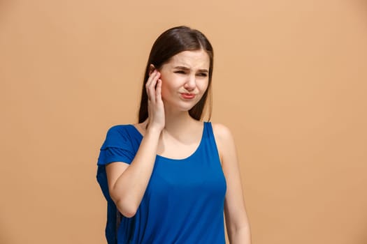 Sore ear. Ear ache concept. The sad crying woman with headache or pain on trendy pastel studio background. Facial expressions and people emotions concept. Front view. Half-length front portrait Young woman.