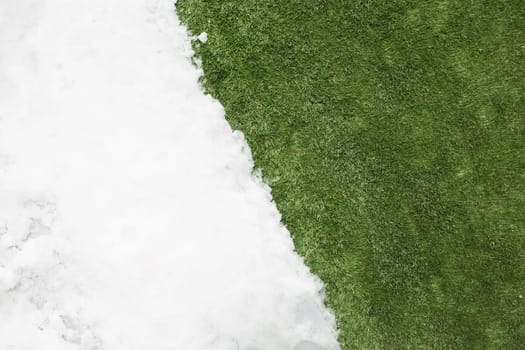 Meeting white snow and green grass close up - between winter and spring concept background. Conceptual image about spring. Selective focus. Background with copy space. Top view