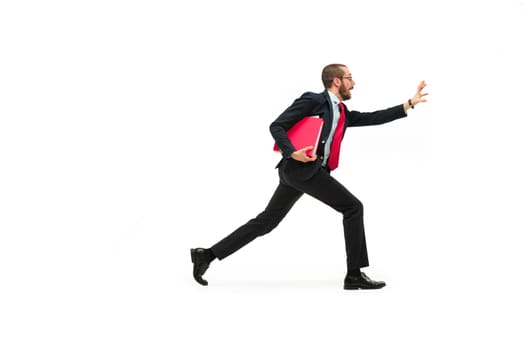 Businessman running with a folder isolated on white background. Full body or full-length portrait of businessman with red folder at studio background. Serious bearded young man in glasses, suit . Business, career, success concept. Profile