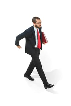 Full body or full-length portrait of businessman going with red folder on white studio background. Serious bearded young man in glasses, suit going in office. Business, career, success concept.