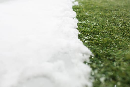 Meeting white snow and green grass close up - between winter and spring concept background. Conceptual image about spring. Selective focus. Background with copy space. Top view