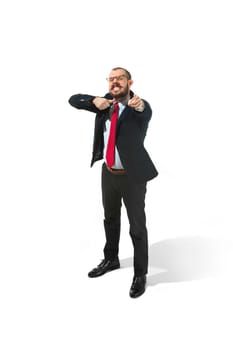 Angry aggressive businessman threatening and pointing to camera. Isolated on white studio background. Serious bearded young man in glasses, suit, red tie. Business, threat, boss concept.