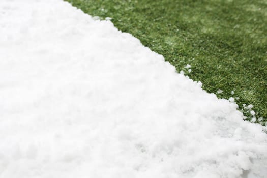 Meeting white snow and green grass close up - between winter and spring concept background. Conceptual image about spring. Selective focus. Background with copy space