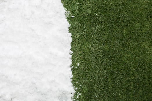 Meeting white snow and green grass close up - between winter and spring concept background. Conceptual image about spring. Selective focus. Background with copy space