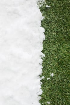 Meeting white snow and green grass close up - between winter and spring concept background. Conceptual image about spring. Selective focus. Background with copy space