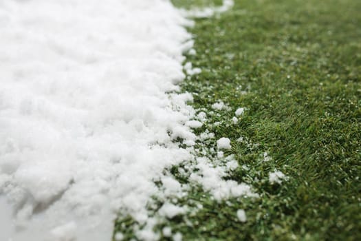 Meeting white snow and green grass close up - between winter and spring concept background. Conceptual image about spring. Selective focus. Background with copy space