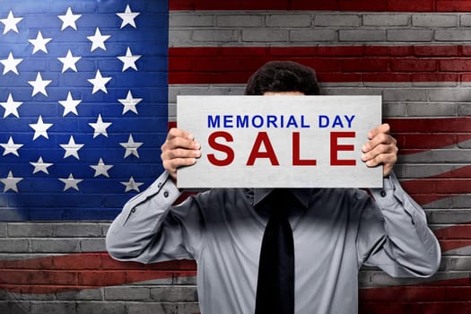 Businessman holding board with memorial day sale sign with american flag background