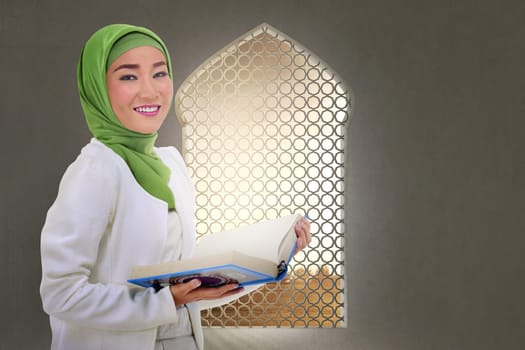 Young asian muslim woman with Koran on the mosque