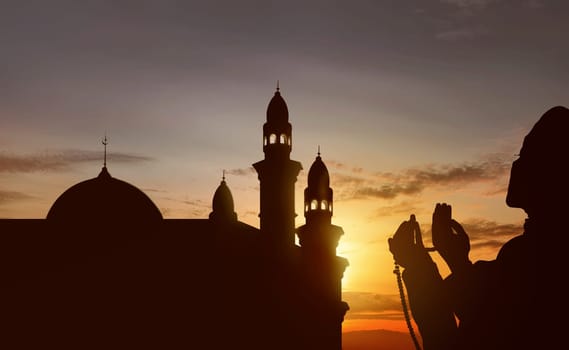 Silhouette of asian muslim praying with prayer beads at sunset background