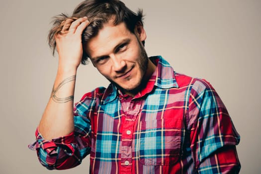 Fashion portrait of a handsome man with trendy hairstyle in a stylish shirt on light green background
