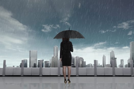Business woman with umbrella in the rain on the city